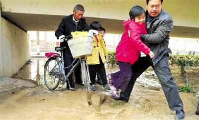 一位好心人把过马路的小学生一个个抱过去。 晚报记者 廖谦图